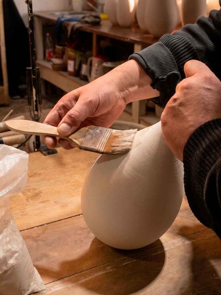 Applying mineral slip by hand with a brush on raw stoneware — Fernando Durao's studio process, Buenos Aires