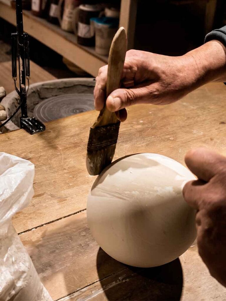 Applying mineral slip by brush to a raw stoneware vase — Fernando Durao's studio process, Buenos Aires